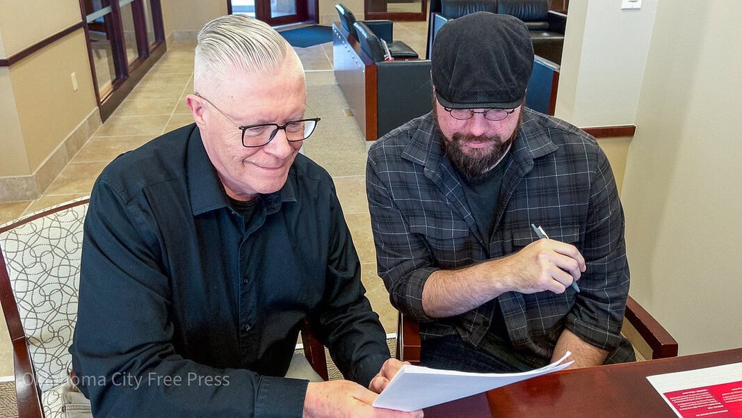 Brett Dickerson on left and Brett Fieldcamp on right look over the transfer of ownership of shares of Oklahoma City Free Press LLC on Monday, Feb. 9. (B.DICKERSON/Okla City Free Press)