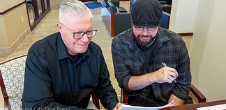 Brett Dickerson on left and Brett Fieldcamp on right look over the transfer of ownership of shares of Oklahoma City Free Press LLC on Monday, Feb. 9. (B.DICKERSON/Okla City Free Press)