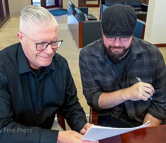 Okla City Free Press gains new leader as founder retires Brett Dickerson on left and Brett Fieldcamp on right look over the transfer of ownership of shares of Oklahoma City Free Press LLC on Monday, Feb. 9. (B.DICKERSON/Okla City Free Press)