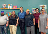 PRESS RELEASE: AutismOklahoma and Delta Dental debut video to ease dentist visit anxiety for people with autism Eight people pose for a group photo in an art studio with colorful paintings on a teal wall behind them.