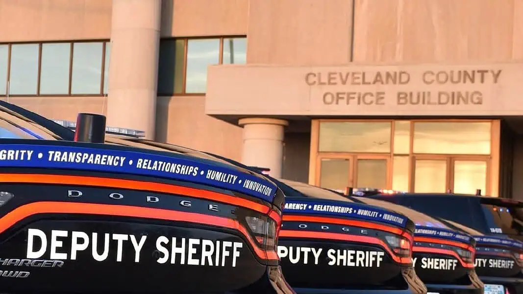 Cleveland County Sheriff Row of black Dodge deputy sheriff patrol cars lined up in front of the Cleveland County Office Building exterior, displaying bold ‘DEPUTY SHERIFF’ lettering.