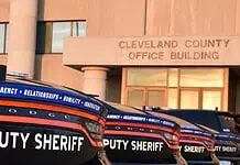 Cleveland County Sheriff resigns following embezzlement plea deal Row of black Dodge deputy sheriff patrol cars lined up in front of the Cleveland County Office Building exterior, displaying bold ‘DEPUTY SHERIFF’ lettering.