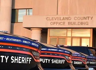 Cleveland County Sheriff resigns following embezzlement plea deal Row of black Dodge deputy sheriff patrol cars lined up in front of the Cleveland County Office Building exterior, displaying bold ‘DEPUTY SHERIFF’ lettering.