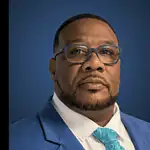 PRESS RELEASE: Metro Tech Board of Education appoints David Martin as Superintendent & CEO Portrait of a Black man in a blue suit, white shirt, and turquoise patterned tie, against a dark blue gradient background.