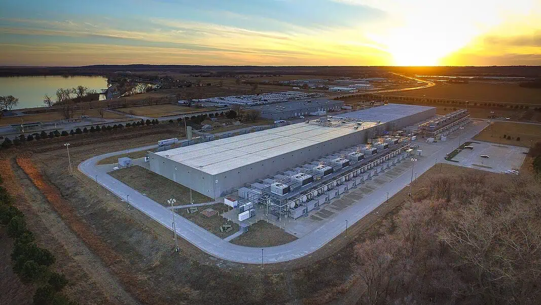 Google Data Center, Council Bluffs Iowa Aerial view of a large industrial warehouse complex at sunset, with rows of equipment along the side and a river nearby.