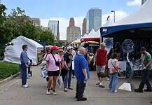 Festival of the Arts kicks off 60th year celebrating art in OKC People walk through an outdoor street fair with white tents and vendors, city skyscrapers in the background.