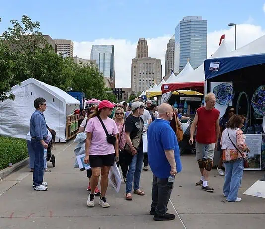 Festival of the Arts kicks off 60th year celebrating art in OKC People walk through an outdoor street fair with white tents and vendors, city skyscrapers in the background.