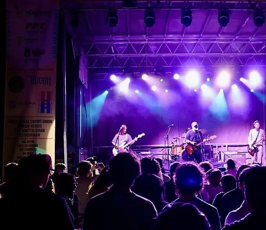 Norman Music Fest defined by feeling, haze, cross-genre range in 2026 Band performs on a lit stage with purple and blue lights as a crowd watches from the foreground at a nighttime concert.