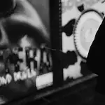 Dark thrillers, artsy horrors sink their teeth into OKC theaters Woman in a dark hooded coat stands in a dim urban street at night, looking worried or sad.