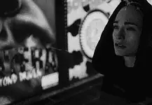 Dark thrillers, artsy horrors sink their teeth into OKC theaters Woman in a dark hooded coat stands in a dim urban street at night, looking worried or sad.