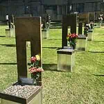 Oklahoma City remembers 31 years since Bombing with solemn focus Rows of bronze and metal grave markers with colorful flowers on a well-kept grassy cemetery lawn.