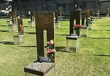 Oklahoma City remembers 31 years since Bombing with solemn focus Rows of bronze and metal grave markers with colorful flowers on a well-kept grassy cemetery lawn.