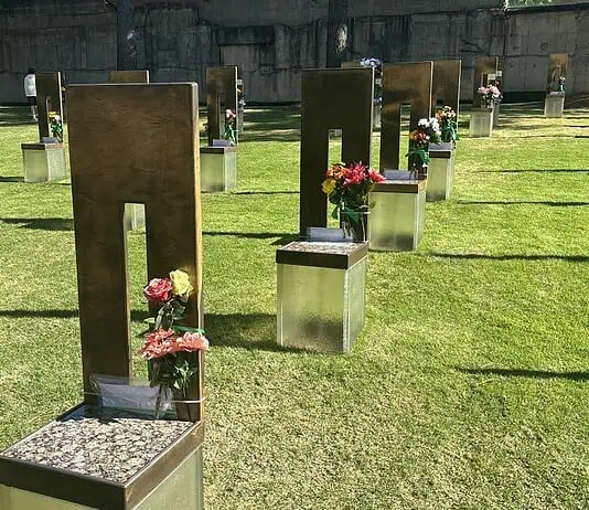 Oklahoma City remembers 31 years since Bombing with solemn focus Rows of bronze and metal grave markers with colorful flowers on a well-kept grassy cemetery lawn.