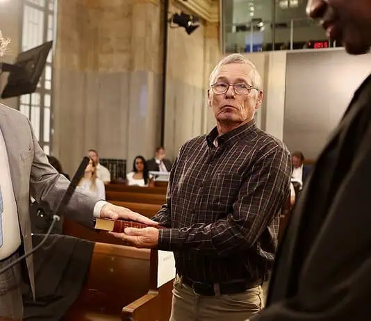 PRESS RELEASE: Brian Young sworn in as Oklahoma City Municipal Court judge Man in a gray suit raises his right hand to take an oath, as another man holds a book for him in a formal setting.