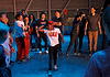 Color of Art returns to showcase diversity of OKC art, dance, music Group of youths forming a circle around a dancer in a white shirt performing a breakdance move under blue lighting.