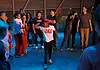 Color of Art returns to showcase diversity of OKC art, dance, music Group of youths forming a circle around a dancer in a white shirt performing a breakdance move under blue lighting.