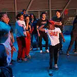 Color of Art returns to showcase diversity of OKC art, dance, music Group of youths forming a circle around a dancer in a white shirt performing a breakdance move under blue lighting.