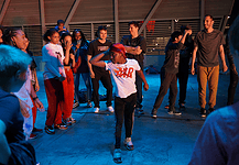 Color of Art returns to showcase diversity of OKC art, dance, music Group of youths forming a circle around a dancer in a white shirt performing a breakdance move under blue lighting.