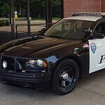 Two-tone Edmond Police patrol car (black and white) with a roof light bar, parked outside a brick building.