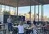 Edmond official says City not investigating police response to shooting A man in a blue sweater speaks to a small audience seated at picnic tables under an outdoor pavilion, with apartment buildings in the background.