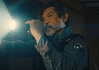 deadCenter features go heavy on history, diversity, modern battles Male officer in uniform shines a flashlight into a dim room, beam across the scene,
