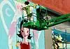 Sunny Dayz Mural Fest heads to Claremore with inclusive art, OKC artists Two workers on a green boom lift painting a colorful mural of a woman with black hair on a brick wall.