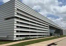 City Council’s data center exemptions raise questions of favoritism Modern white building with horizontal slat facade and a glass entrance, surrounded by a grassy lawn under a blue sky.