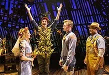 Country comedy ‘Shucked’ a corn-fed good time at Civic Center Actor in a leafy, harvest-themed costume raises arms on stage as four costumed performers look on with smiles on a wooden theater set.