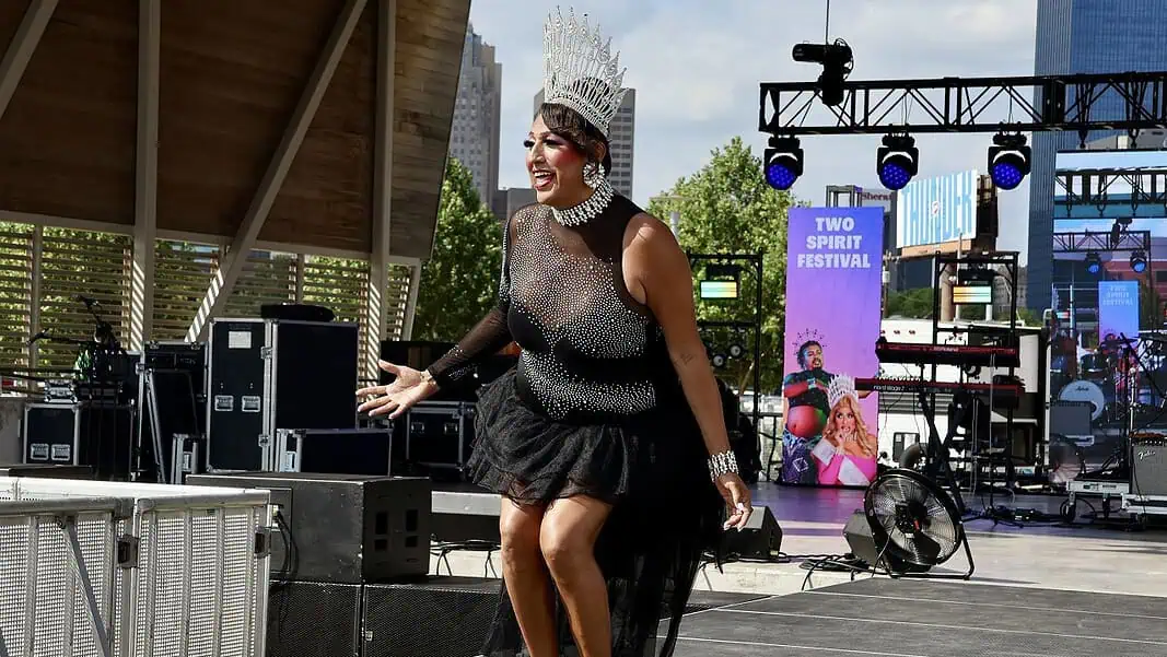 IMG_0357 Drag performer wearing a tall silver crown and black sequined outfit performing on an outdoor stage at the Two Spirit Festival