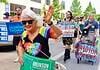 Oklahoma Pride Alliance looks beyond Pride Month Older woman with white hair in a rainbow shirt and sunglasses waves at a Pride parade, holding a green campaign sign for Cyndi Munson for Governor.