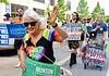 Oklahoma Pride Alliance looks beyond Pride Month Older woman with white hair in a rainbow shirt and sunglasses waves at a Pride parade, holding a green campaign sign for Cyndi Munson for Governor.