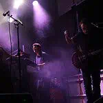 Crank up the summer with these hard-driving rock and metal shows Live music performance on a foggy stage with purple lighting; female singer left, keyboardist center, guitarist right.