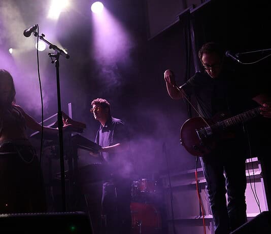 Crank up the summer with these hard-driving rock and metal shows Live music performance on a foggy stage with purple lighting; female singer left, keyboardist center, guitarist right.
