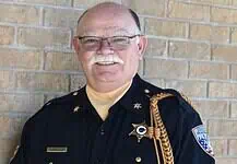 PRESS RELEASE: Francis Tuttle instructor named regional Teacher of the Year Older male sheriff in uniform smiling against a brick wall, with gold braid and badge.