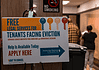 Poster offering free legal services for tenants facing eviction in a hallway; no smoking sign above and people in the background.