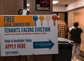 OKC evictions have doubled in a decade Poster offering free legal services for tenants facing eviction in a hallway; no smoking sign above and people in the background.