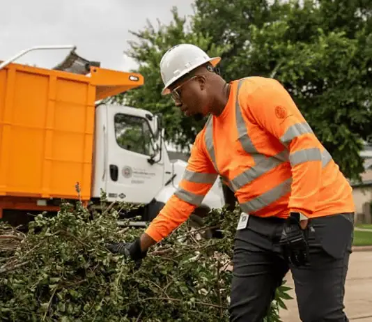 PRESS RELEASE: June storm debris to be collected in OKC on regular July bulky waste schedule Utility worker in an orange safety vest and hard hat clearing storm debris beside a city dump truck; green panel on the right reads 'UPDATE June Storm Debris Collection' with city seal.