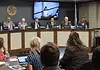 Oklahoma Turnpike Authority seeks $1.5B in bonds for construction costs Panel of officials seated at a curved dais in a government hearing room, seal on the wall and large screens showing a speaker behind them, audience in foreground.