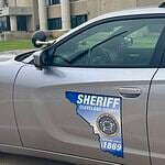 Side of a silver sheriff patrol car with a Cleveland County badge and an Ohio-shaped decal reading 'Serving since 1889'.