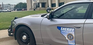 Side of a silver sheriff patrol car with a Cleveland County badge and an Ohio-shaped decal reading 'Serving since 1889'.