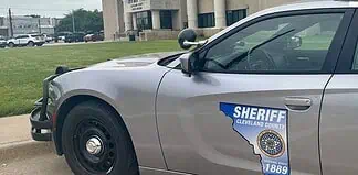 Side of a silver sheriff patrol car with a Cleveland County badge and an Ohio-shaped decal reading 'Serving since 1889'.