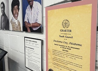 Freedom Center unveils restoration with ‘Inside These Walls’ exhibition Wall exhibit with four large portraits of diverse adults, plus a yellow CHARTER poster labeled 'Youth Council' on a pink mat, and a framed council advisory list nearby, in a museum-like setting.