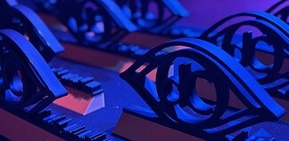 Close-up of ornate black metal eye-shaped sculptures resting on a keyboard, lit in blue and purple stage lighting.