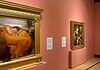 OKCMOA welcomes breadth, beauty of art from famed Puerto Rican museum Large ornate gold-framed painting on a pink wall, depicting a woman in an orange dress resting; to its right, a smaller framed religious-style artwork on a pedestal, also on pink wall.