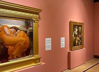 OKCMOA welcomes breadth, beauty of art from famed Puerto Rican museum Large ornate gold-framed painting on a pink wall, depicting a woman in an orange dress resting; to its right, a smaller framed religious-style artwork on a pedestal, also on pink wall.