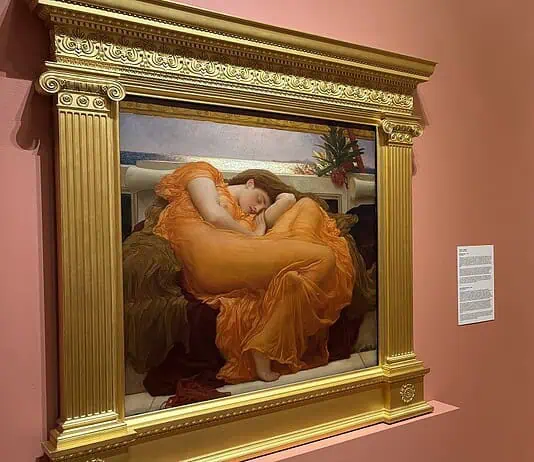 OKCMOA welcomes breadth, beauty of art from famed Puerto Rican museum Large ornate gold-framed painting on a pink wall, depicting a woman in an orange dress resting; to its right, a smaller framed religious-style artwork on a pedestal, also on pink wall.