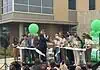 City, nonprofit, service leaders cut ribbon on new Diversion Hub Group of people on a stage cutting a white ribbon at a grand opening, with green balloons behind them.