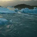 New doc ‘Time and Water’ at OKCMOA a staggering eulogy for nature Icebergs floating in a calm glacial lagoon at sunset with distant mountains in the background, reflecting on the water.