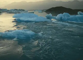 New doc ‘Time and Water’ at OKCMOA a staggering eulogy for nature Icebergs floating in a calm glacial lagoon at sunset with distant mountains in the background, reflecting on the water.