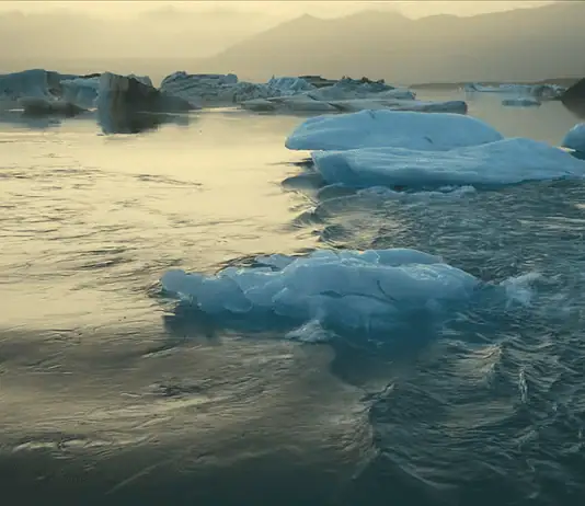 New doc ‘Time and Water’ at OKCMOA a staggering eulogy for nature Icebergs floating in a calm glacial lagoon at sunset with distant mountains in the background, reflecting on the water.
